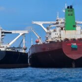 Two large oil tankers sit side-by-side at sea while conducting a ship-to-ship oil transfer in waters off Malaysia.